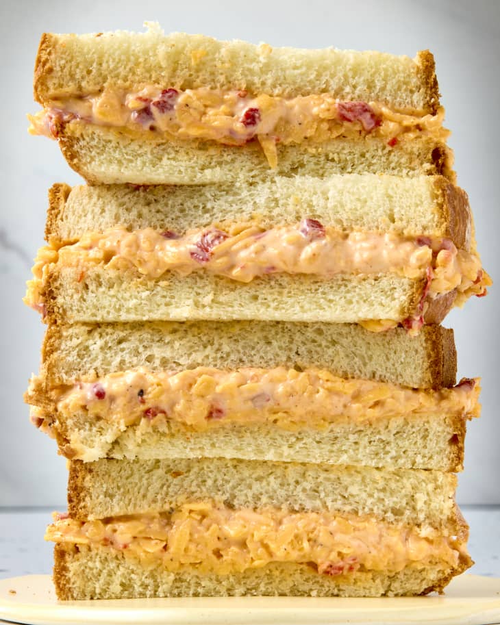 head on shot of four halves of a pimento cheese sandwich on white bread, all stacked on top of each other.