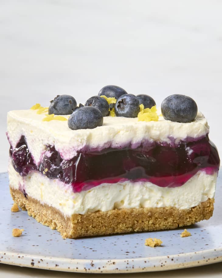 head on shot of lemon blueberry delight on a light blue speckled plate, topped with fresh blueberries and lemon.