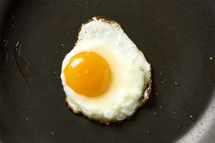 overhead shot of a fried egg being made in vegetable oil.