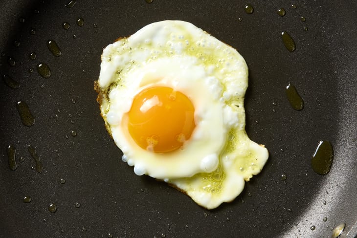 overhead shot a fried egg being cooked in olive oil