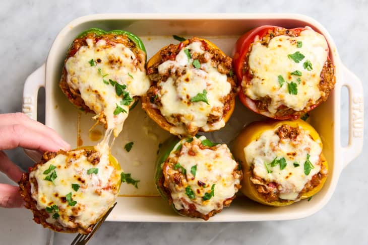 six stuffed peppers in baking dish; one being pulled