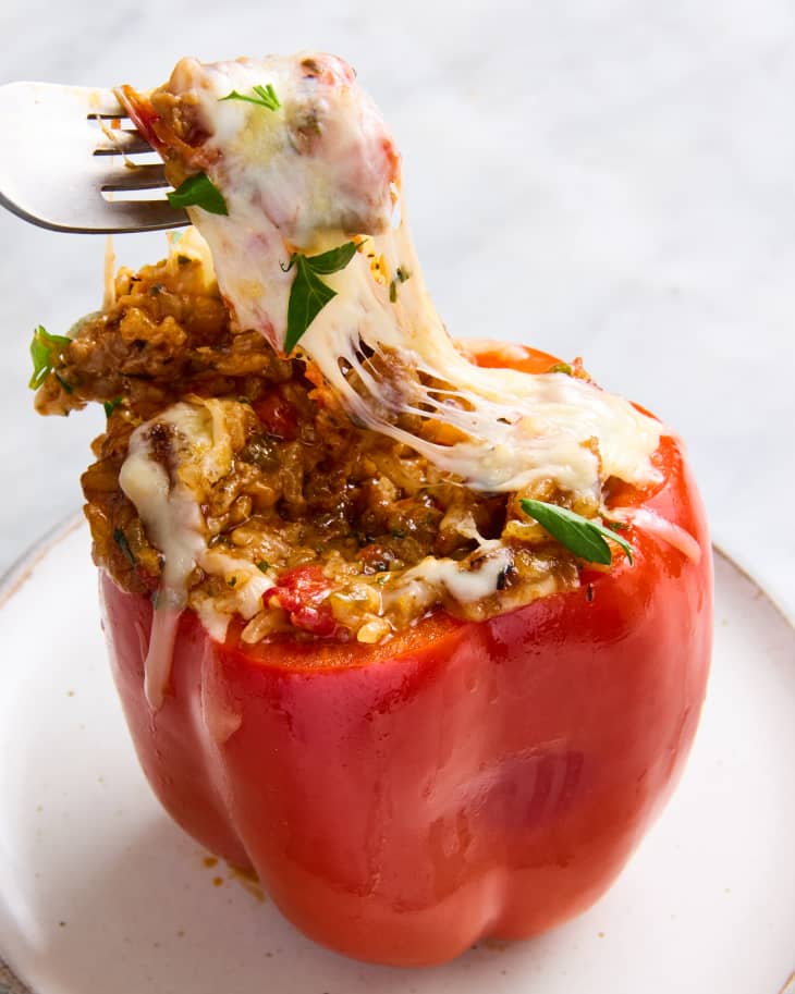 someone pulling cheese off top of stuffed pepper with a fork