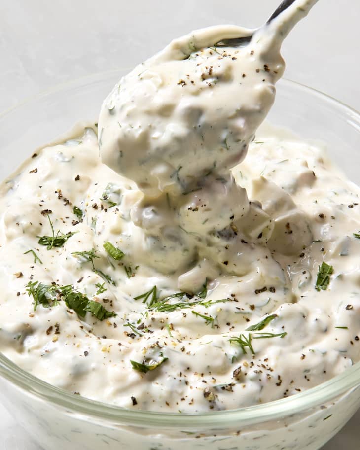 angled shot of a bowl of tartar sauce, topped with herbs.