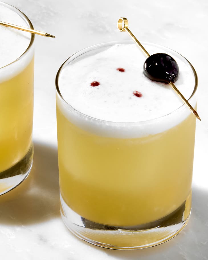 angled shot of a single whiskey sour, garnished with a luxardo cherry.