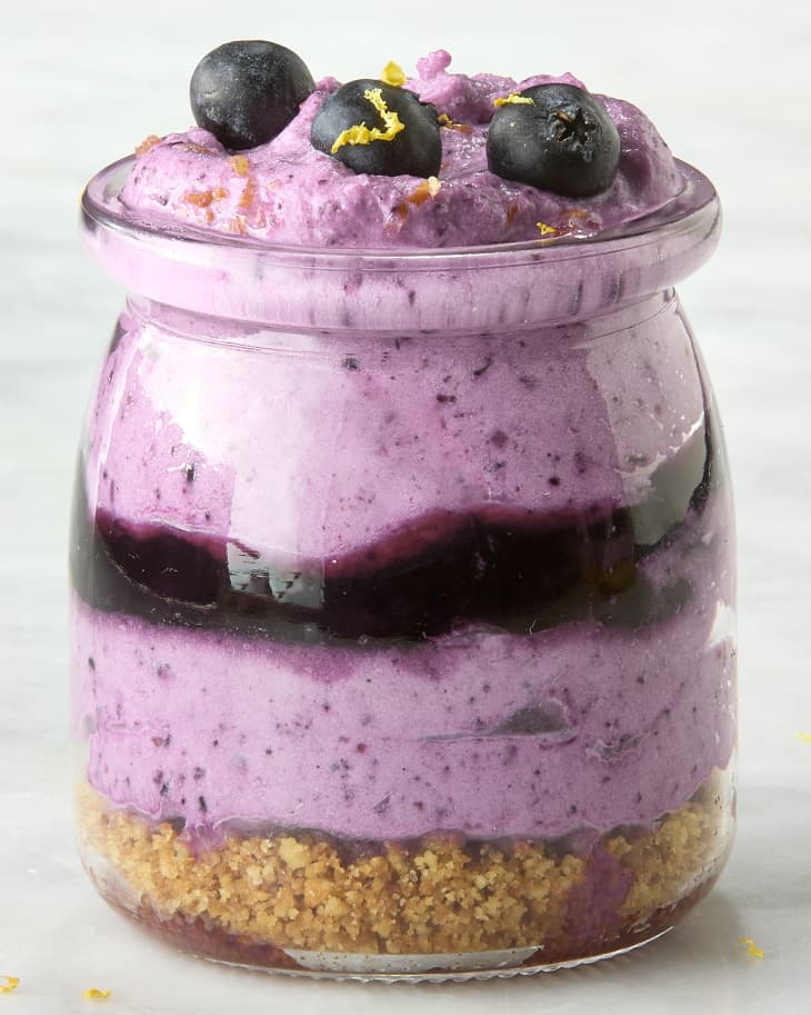 head on shot of a single blueberry mousse in a small jar, topped with lemon zest and three blueberries