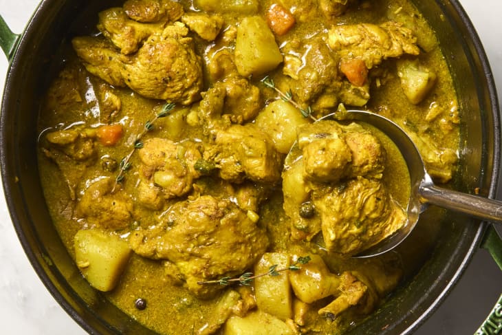 overhead shot of jamaican chicken curry in a large dark green pot.