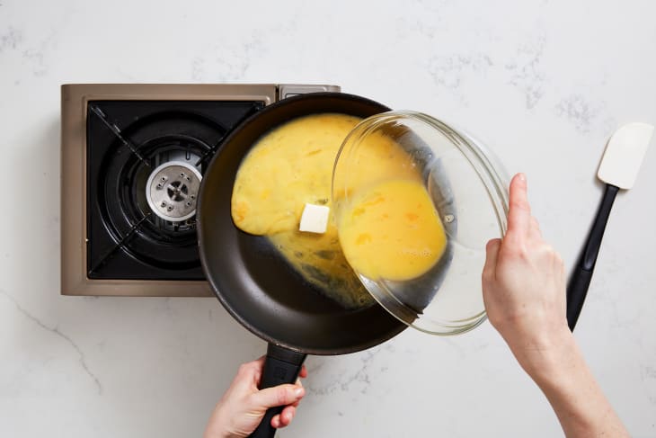 Pouring whisked eggs into non-stick skillet