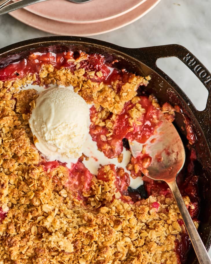 closeup of strawberry rhubarb crisp in cast iron skillet with a scoop of ice cream
