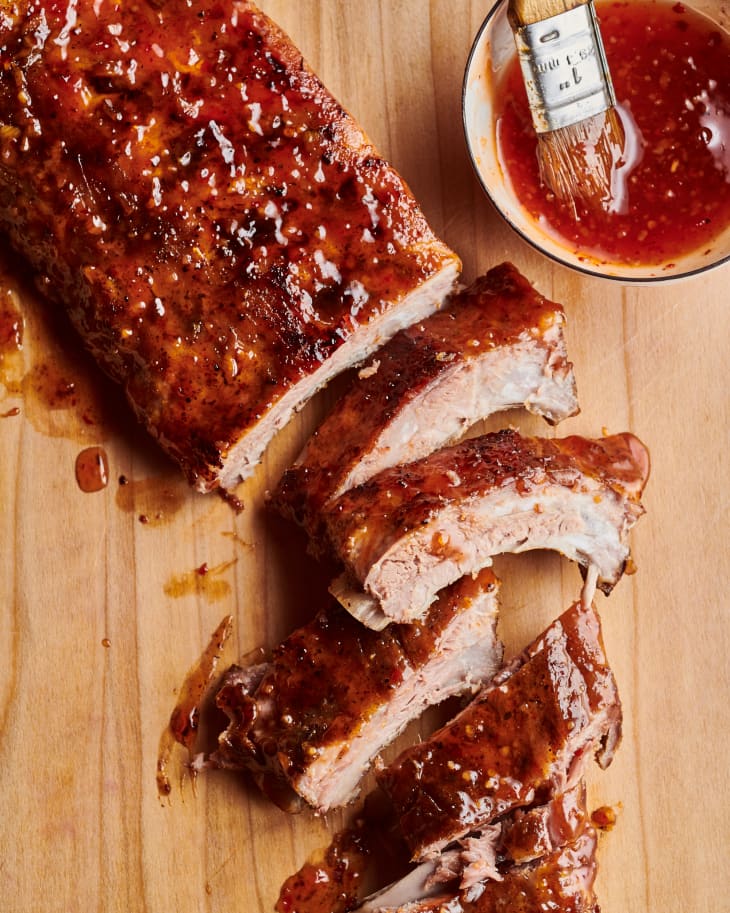 ribs on a cutting board with a small dish of barbecue sauce