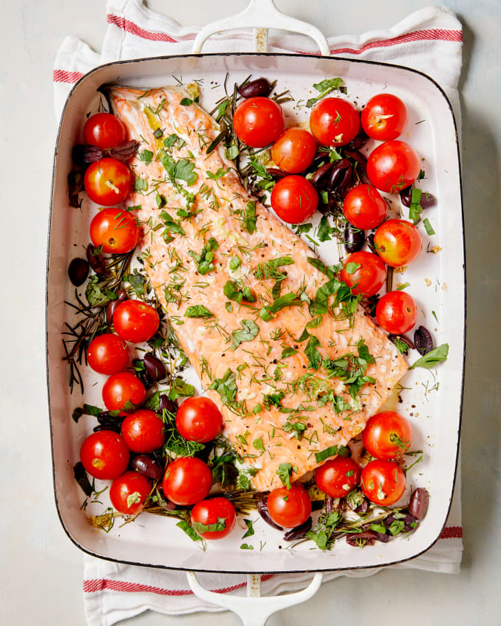The slow-roasted salmon is roasted in a large sheet pan with olives, tomatoes, and herbs.