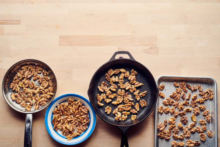 Toasted walnuts in various cooking methods; left to right: stainless steel skillet, small bowl, cast iron skillet. baking sheet.