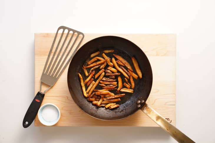 French fries in skillet with spatula beside.