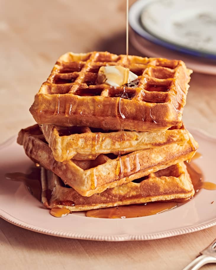 Syrup pouring over a stack of waffles.