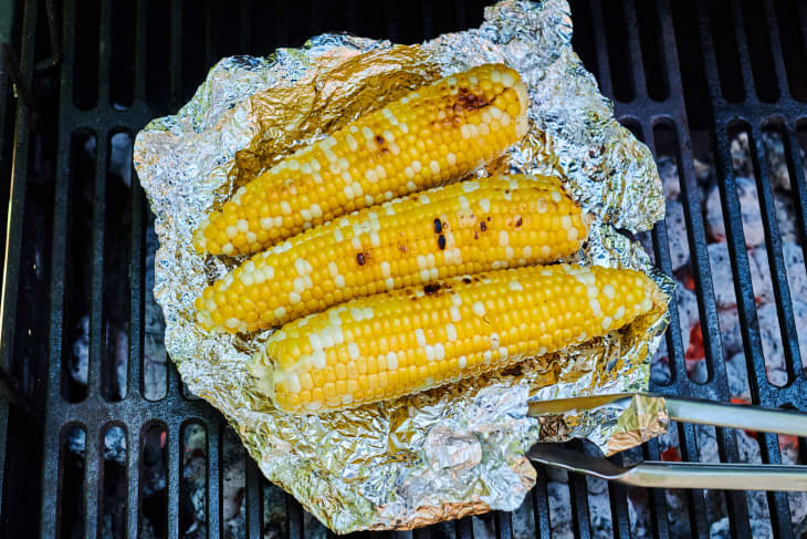 Corn is wrapped in aluminum and cooked over the grill.