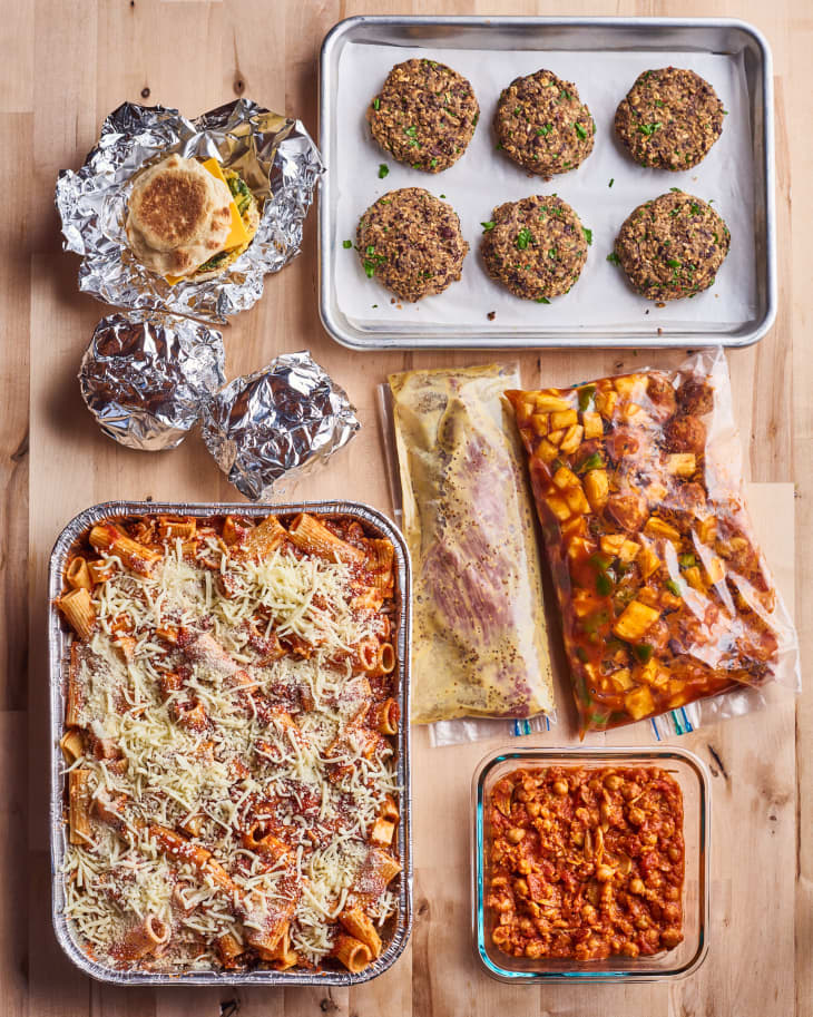 different foods sit in different containers; one on a sheet pan, one on a small glass pyrex container, two wrapped in tin foil, ready to go in the freezer
