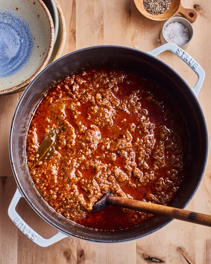 Anne Burrell's bolognese sauce sits in a pasta pot with a wooden spoon in it