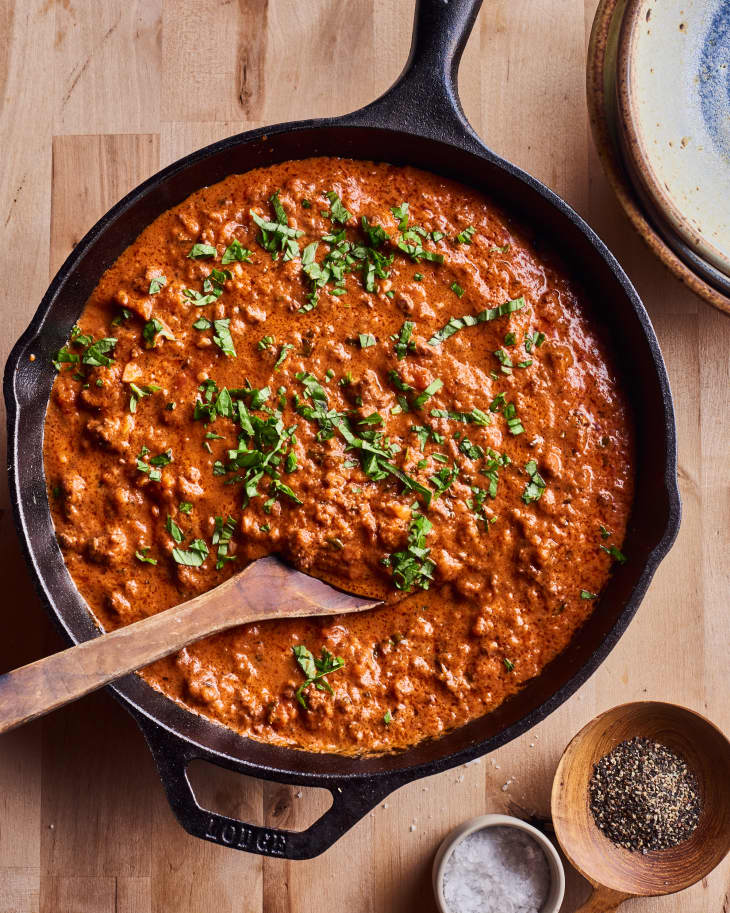 Ina Garten's bolognese sits in a black skillet on a wooden table