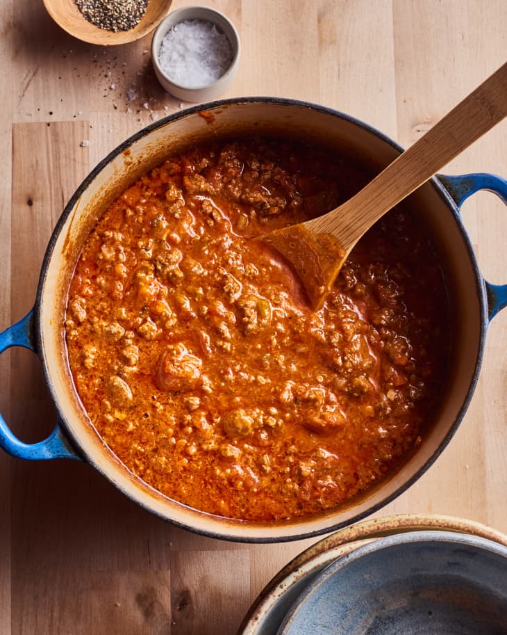 grace parisi's bolognese sits in a pasta pot with a wooden spoon in it