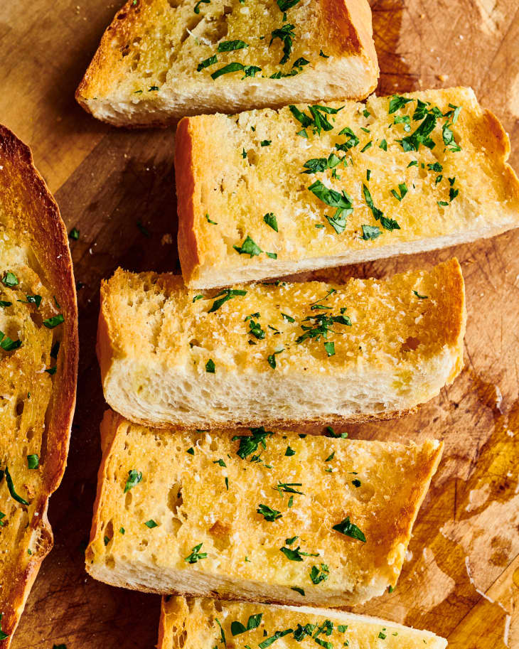 slices of garlic bread sit on a wooden table