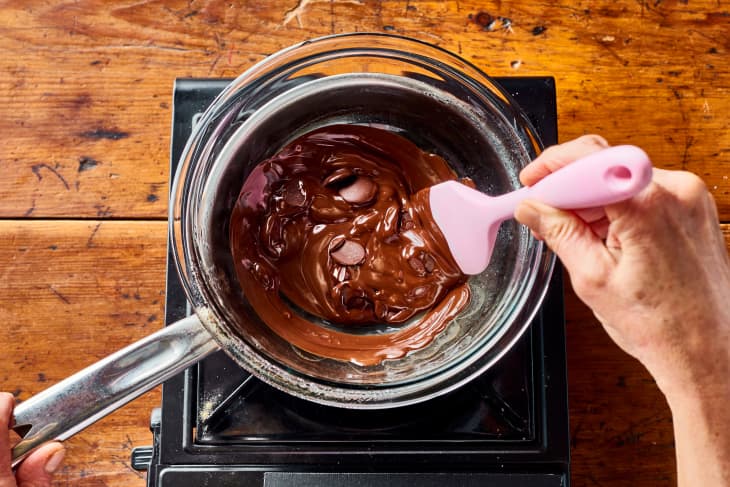 someone is stirring chocolate in a metal bowl on top of a pot