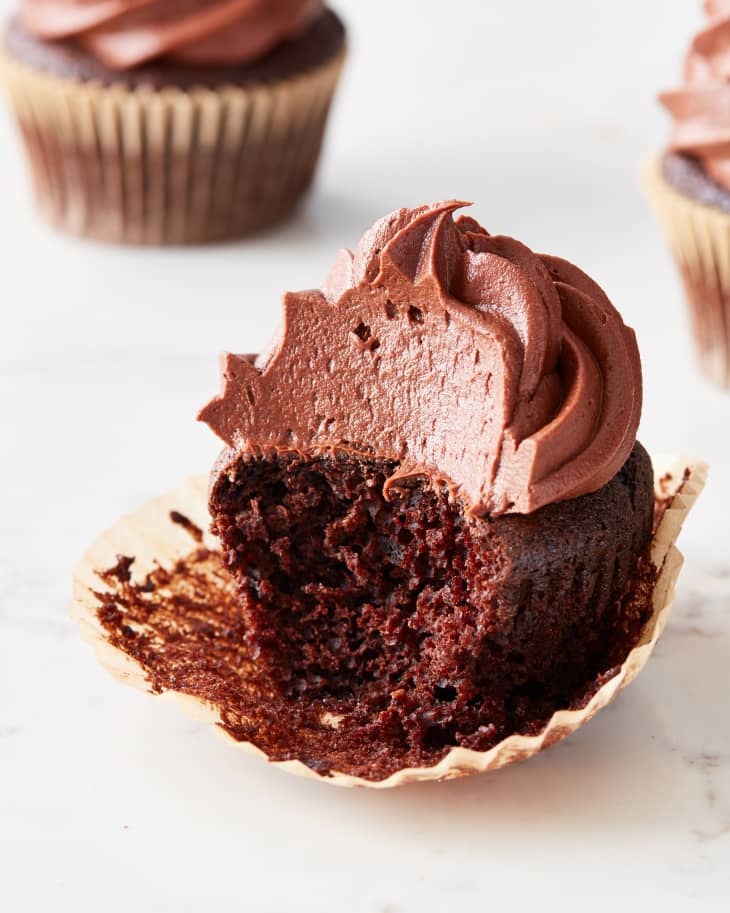 chocolate cupcake sits on a table with a bite taken out of it