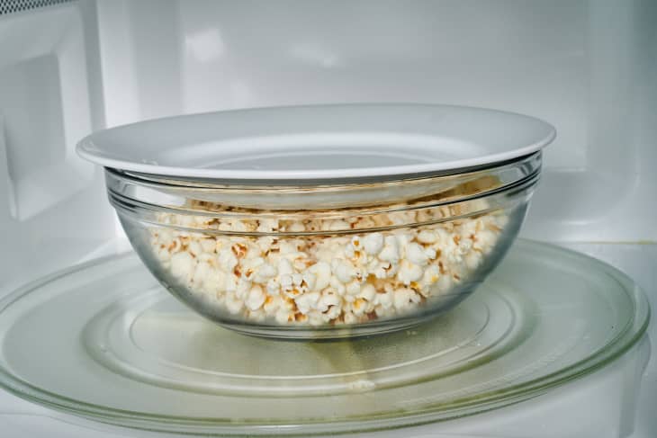 popcorn is in the microwave covered by a bowl
