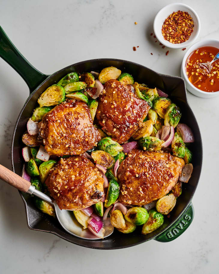 finished chicken sits on top of sprouts and onion in cast iron skillet