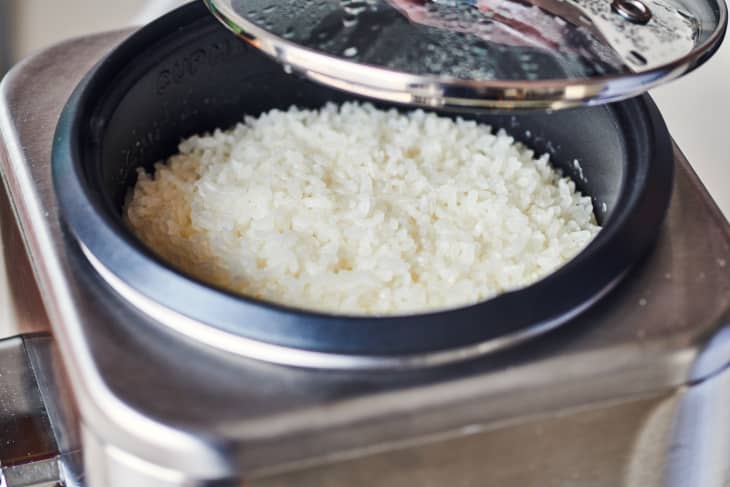 someone is taking the lid off of sushi rice in a rice cooker