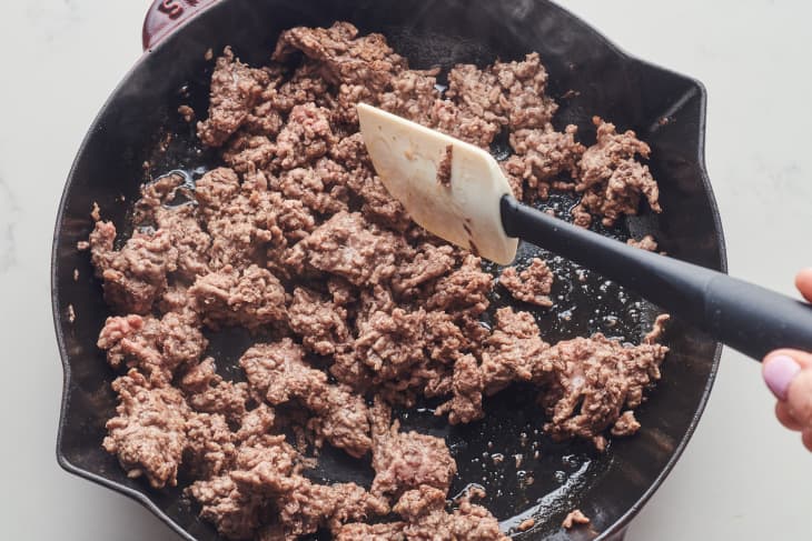 someone is stirring ground beef with a rubber spatula