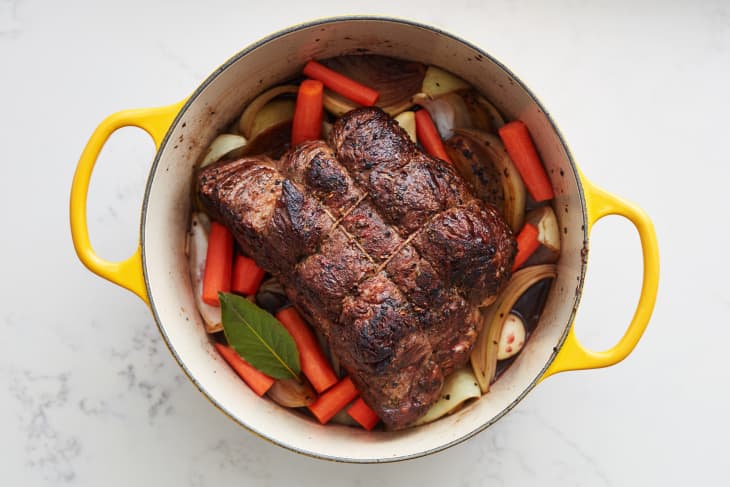 beef sits cooked on top of a pot full of vegetables