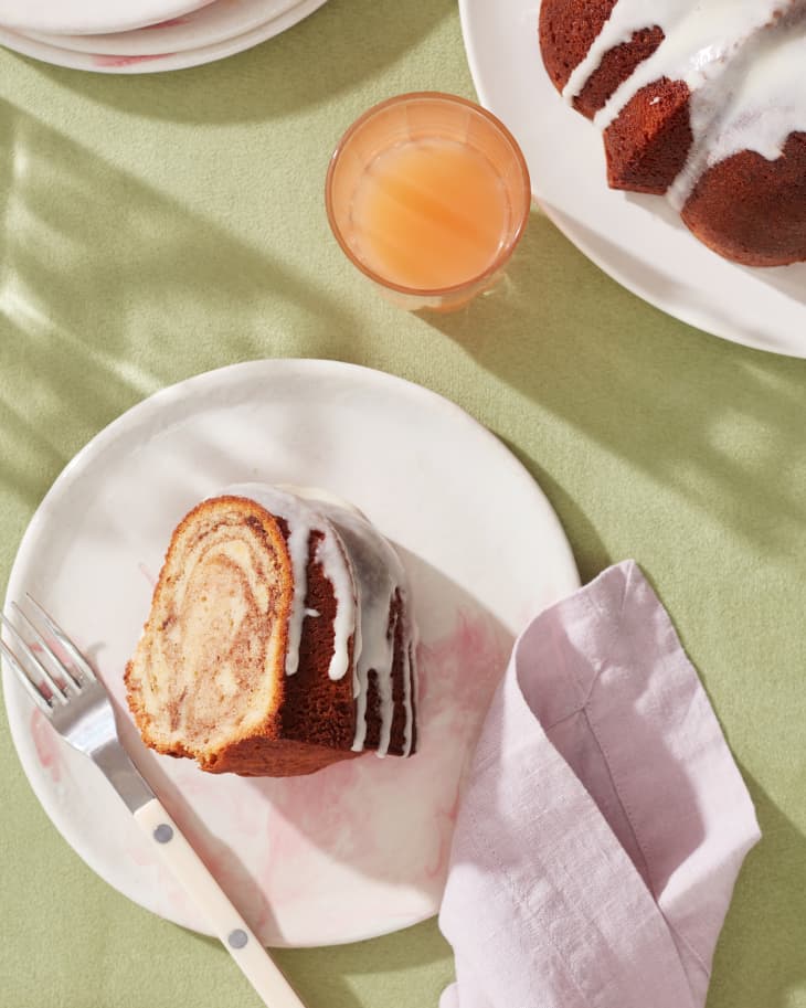 cinnamon roll pound cake slice sits on a plate with cutlery and full pound cake in background