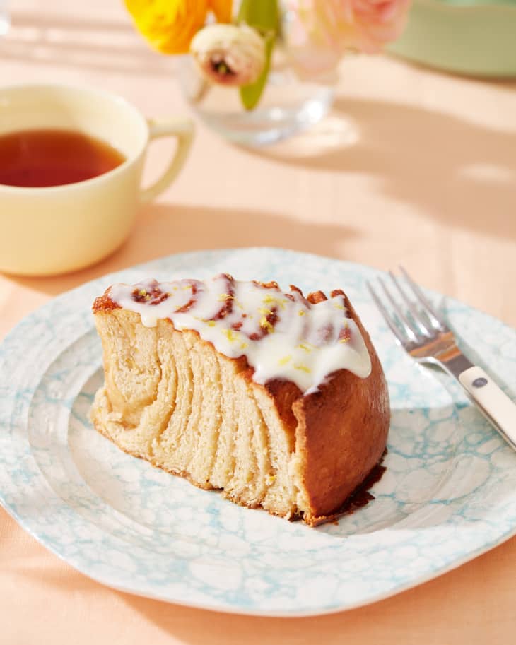 lemon roll cake sliced on a plate next to tea
