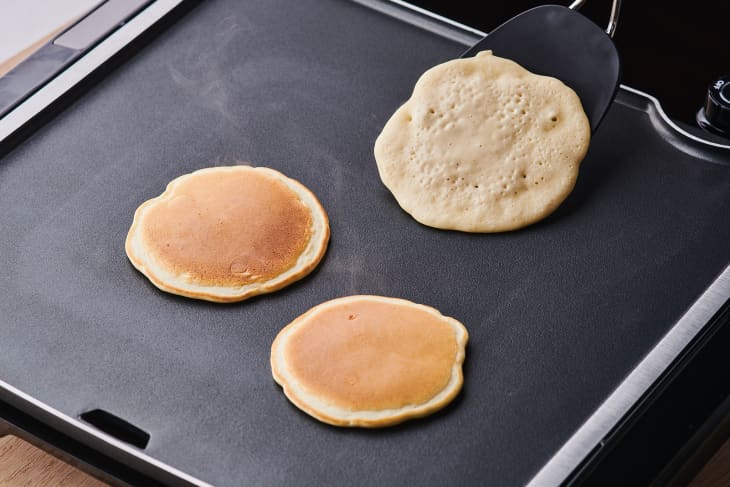 pancakes being flipped on an electric griddle