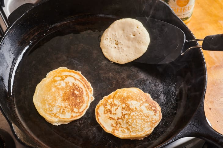 pancakes being flipped on a cast iron pan