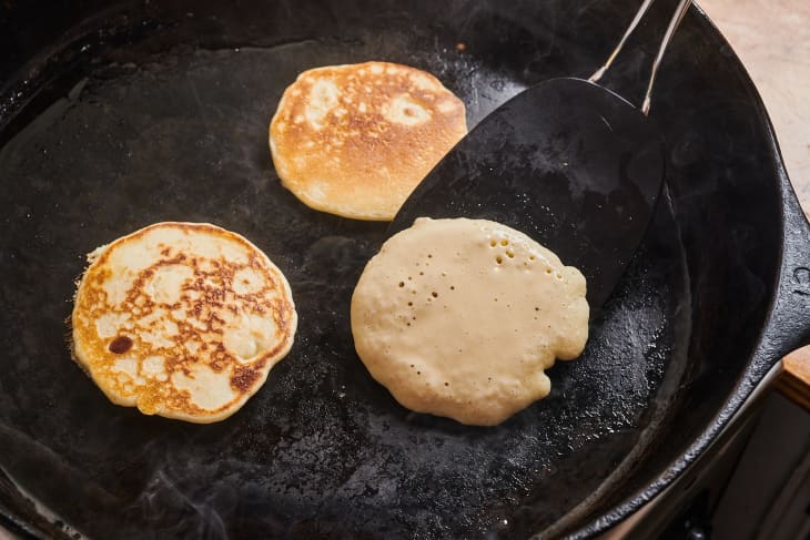 pancakes being flipped on a cast iron pan