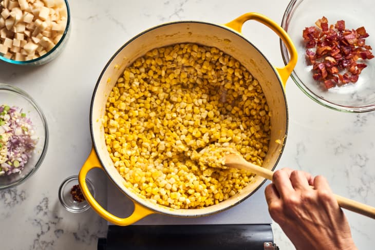 someone mixing corn in pot