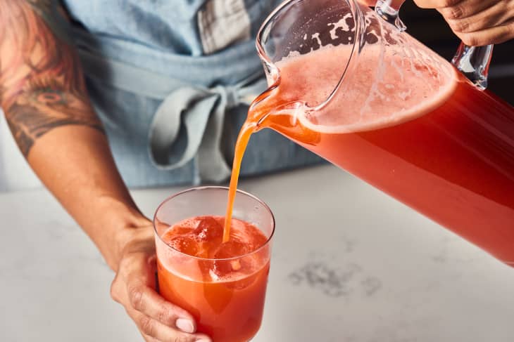 someone pouring strawberry lemonade in a glass