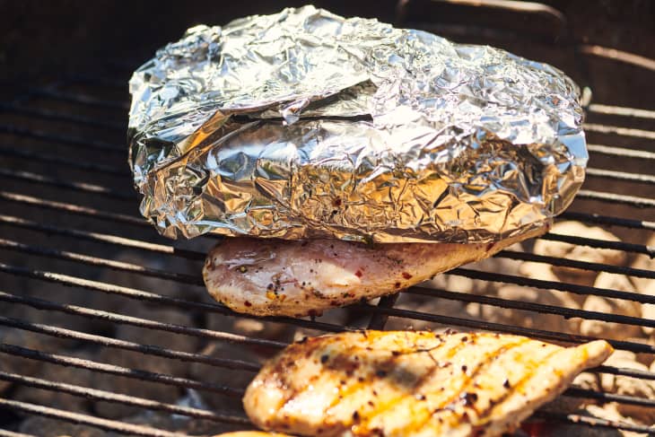 chicken being grilled with brick on top