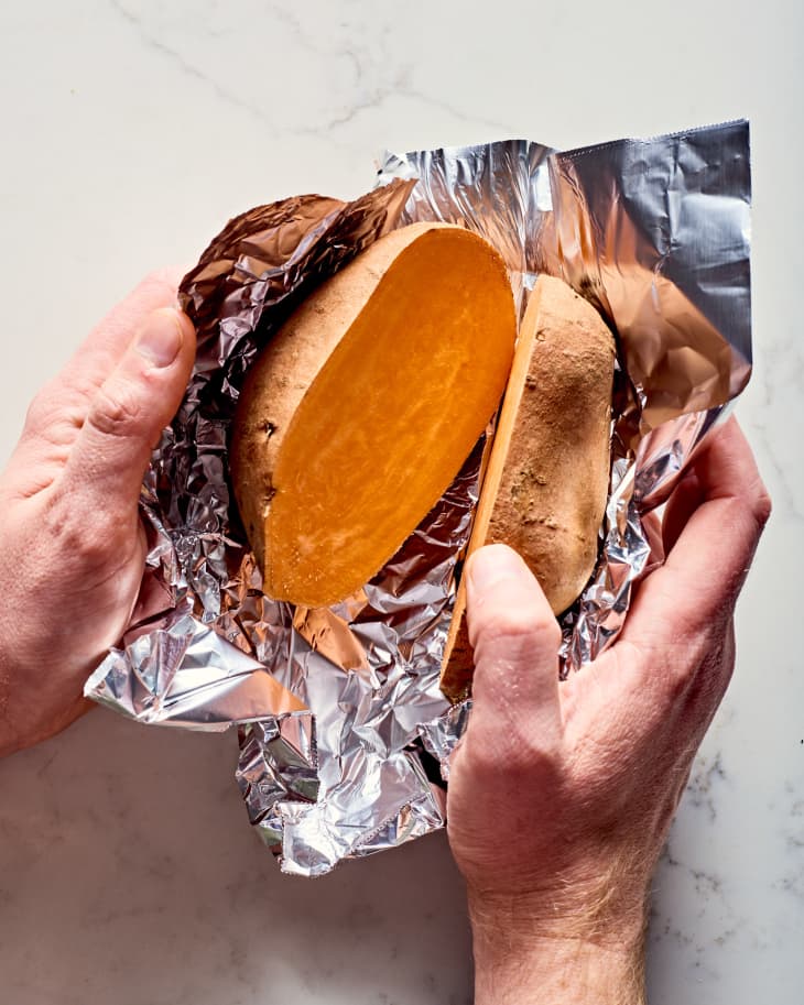 a halved sweet potato being wrapped in foil
