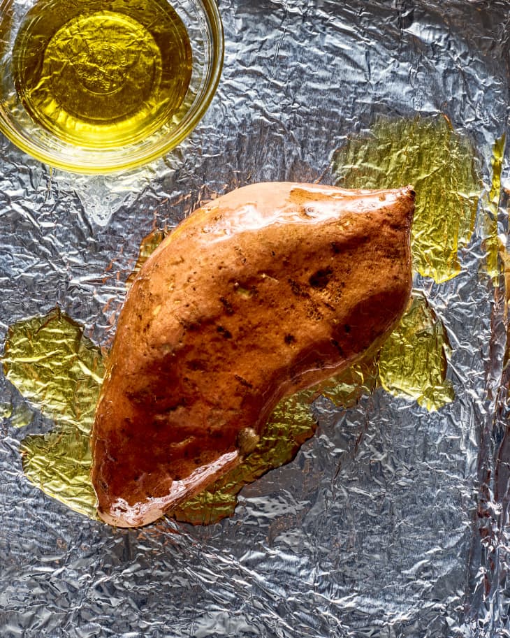 a sweet potato on a sheet pan, rubbed with olive oil