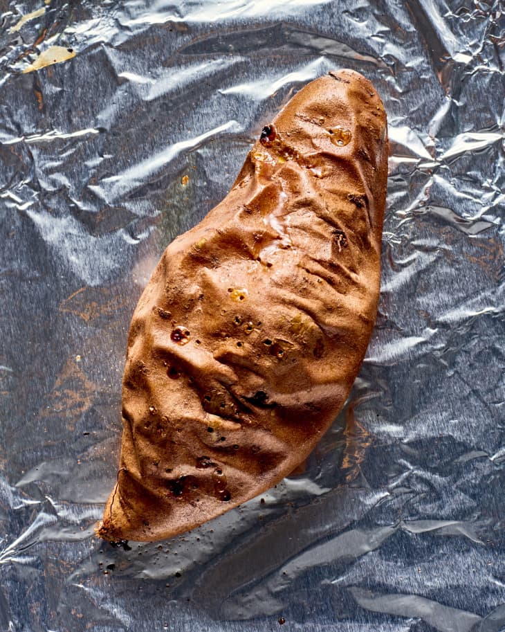 a roasted sweet potato on a foil-lined sheet pan.