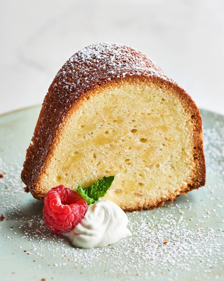 slice of pound cake on plate with powdered sugar, cream, and strawberry