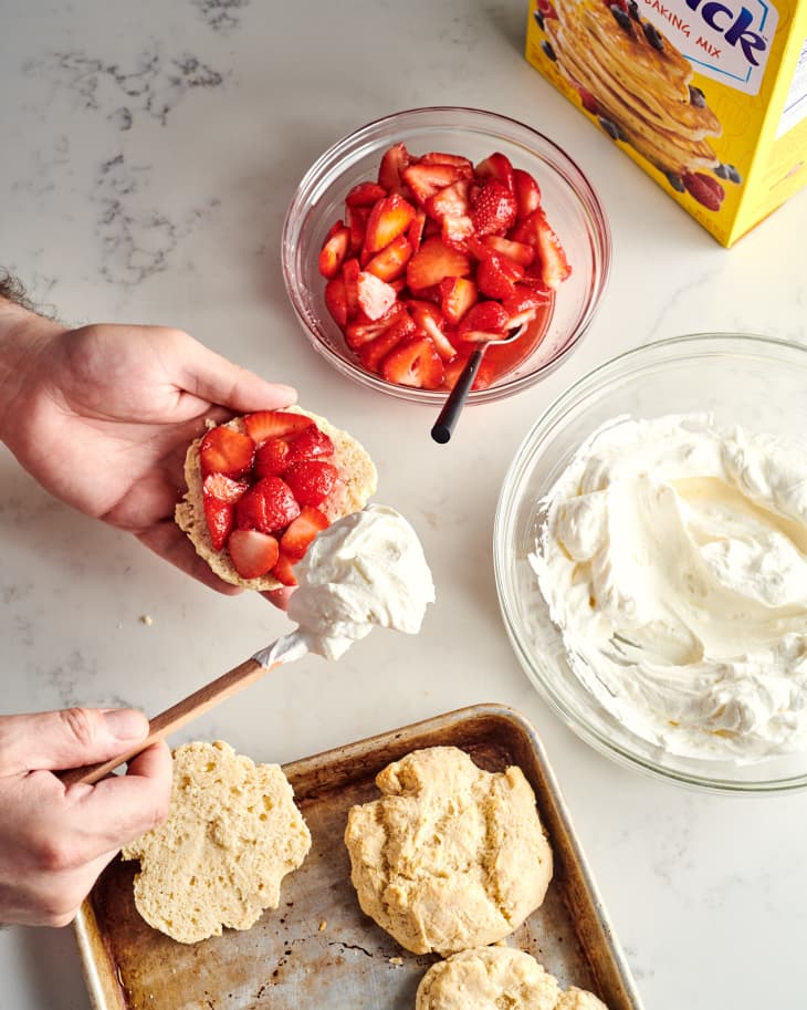 someone is putting cream on the strawberry shortcake