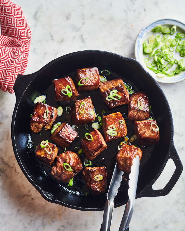 honey balsamic steak bites are cooking in a cast iron skillet