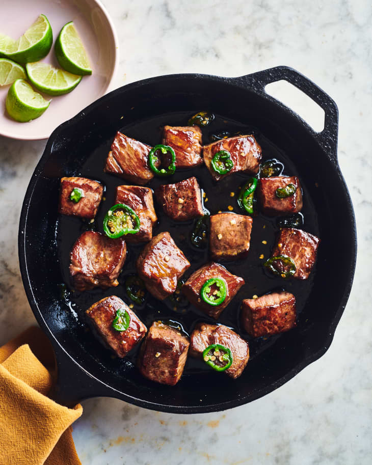sweet and spicy steak bites cooking in a cast iron skillet