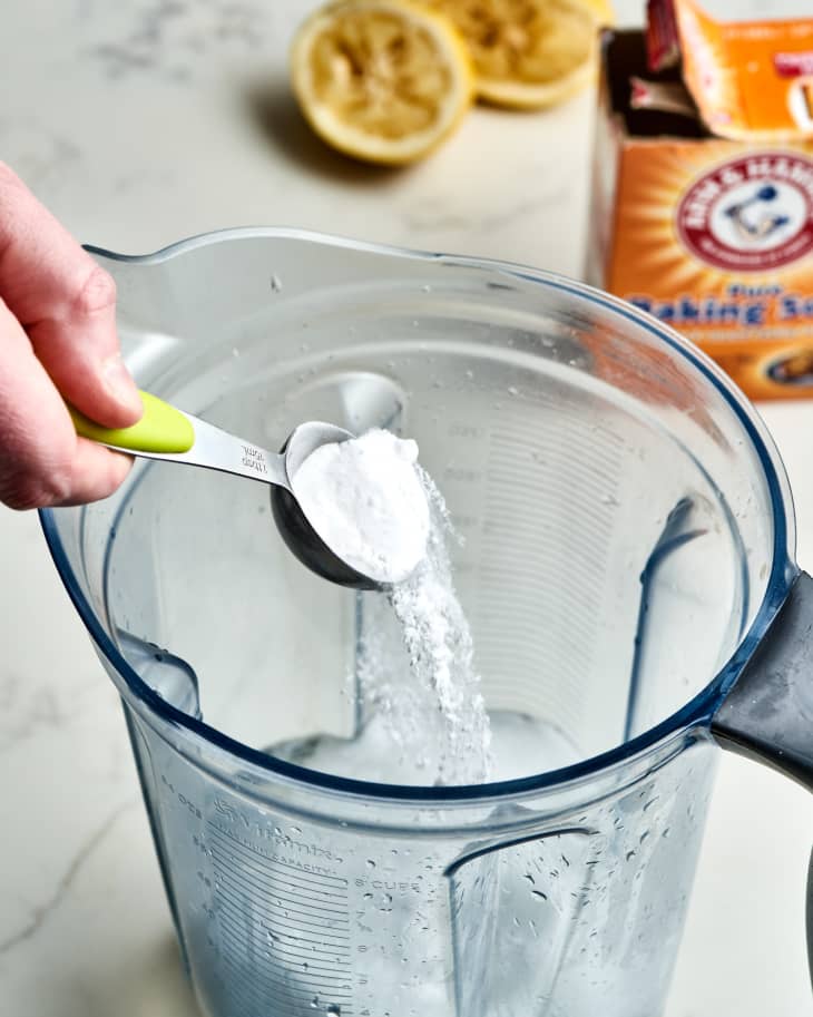 hand pouring baking soda into blender