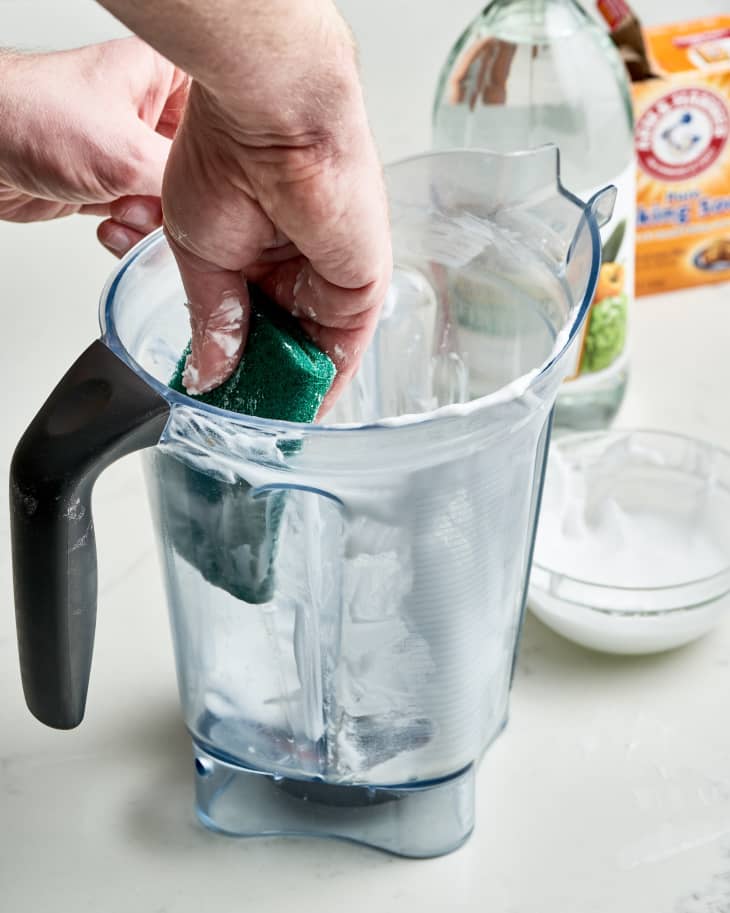 hand scrubbing inside of blender carafe with baking soda paste