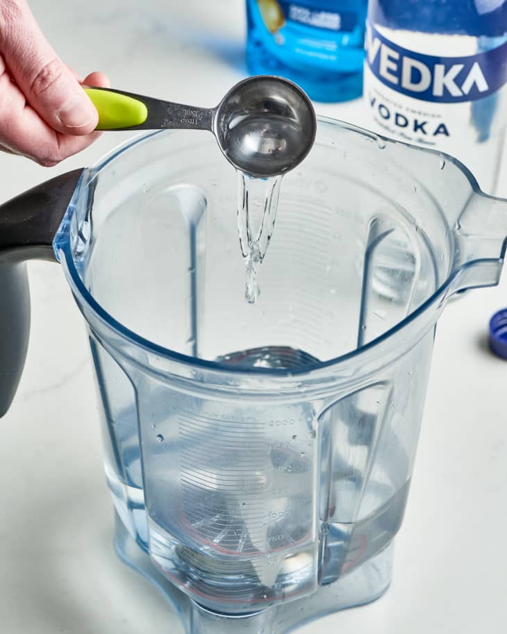hand dribbling vodka into a blender