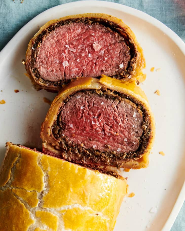 Overhead shot of beef Wellington on a platter, two slices cut crosswise and laid flat to show interior