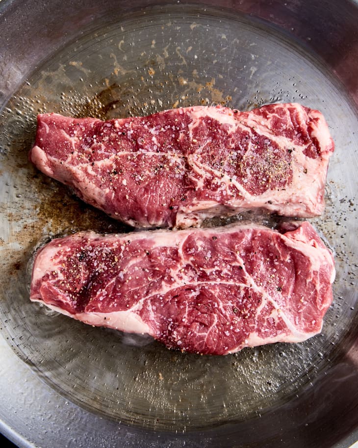 NY strip steak searing in pan
